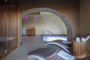 Un espace de détente comprenant deux fauteuils inclinables, un meuble en bois et une arche en pierre.