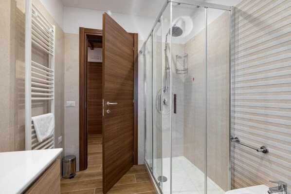 Une salle de bain moderne avec une douche à parois de verre, une porte en bois et un porte-serviettes.