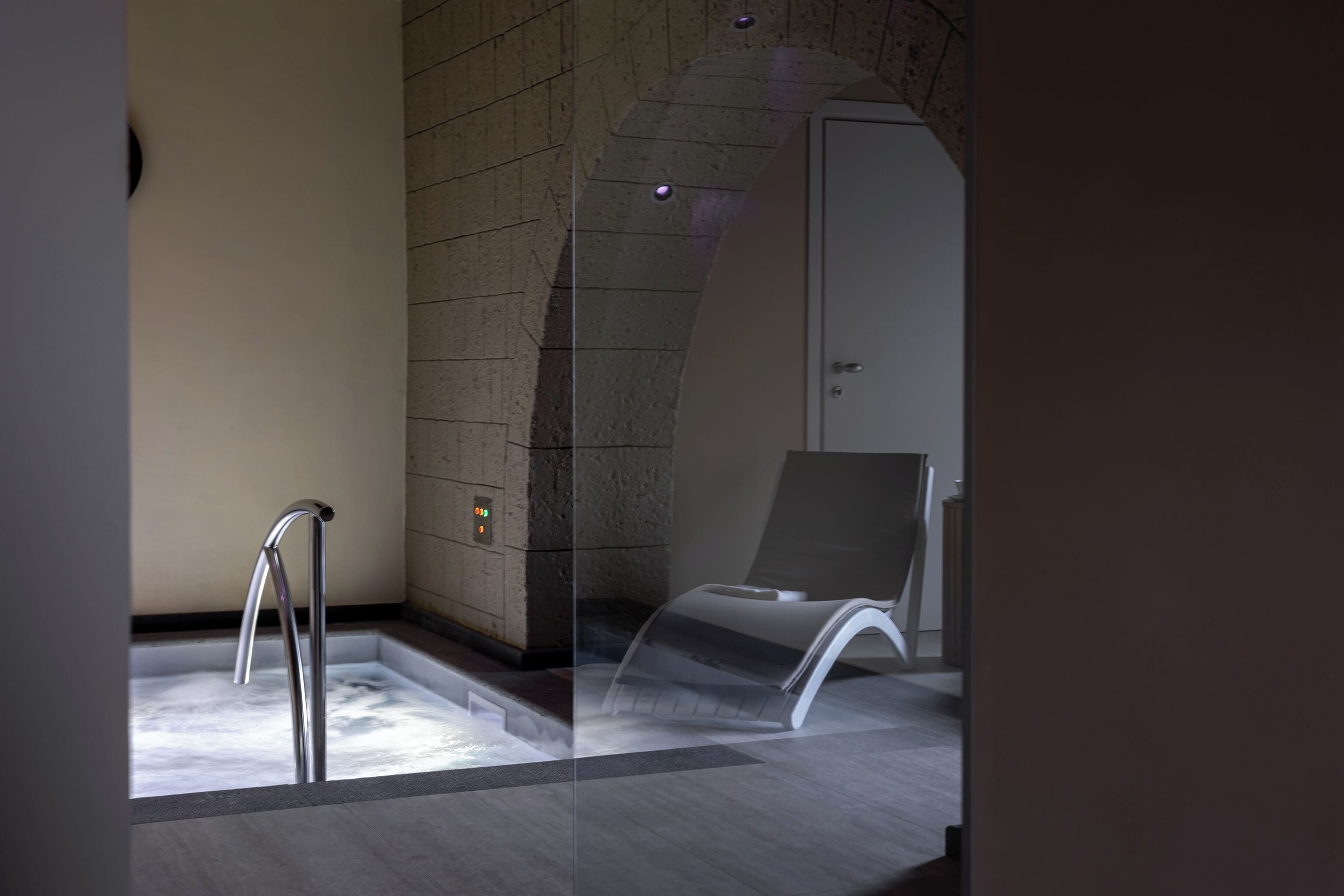 Une salle de bain moderne dotée d’une baignoire, d’une douche et d’un espace détente séparé par une paroi de verre.