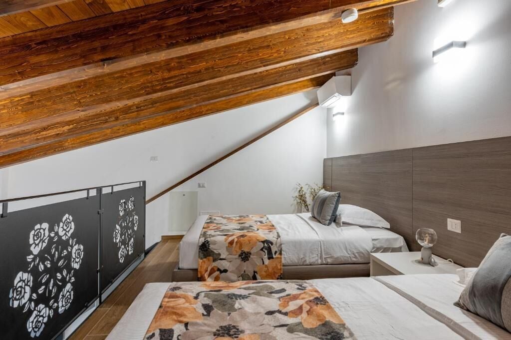 A bedroom with two beds, wooden ceiling beams, and a modern design.