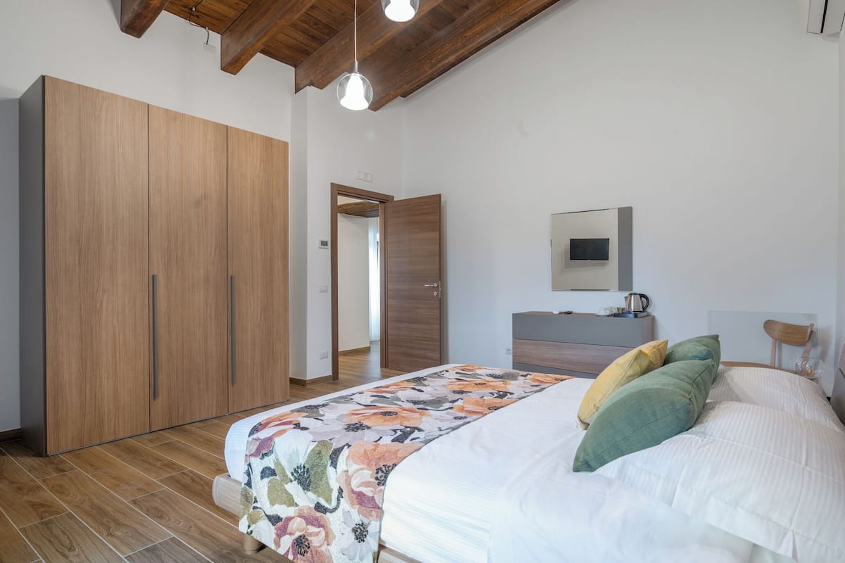 Une chambre à coucher avec un lit, une armoire en bois et un miroir au mur.