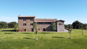 Un edificio in pietra di due piani con tetto piatto, un ingresso centrale e una piccola scala che conduce al piano superiore.