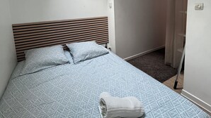 A bedroom with a bed, a skylight, a wooden headboard, and a towel on the bed. - Cosy F2 separate sleeping area on ground floor in quiet pedestrian alley close to all amenities (Orléans)