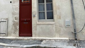 A building with a traditional half-timbered facade, a red door, and a window with a white frame. - Cosy F2 separate sleeping area on ground floor in quiet pedestrian alley close to all amenities (Orléans)