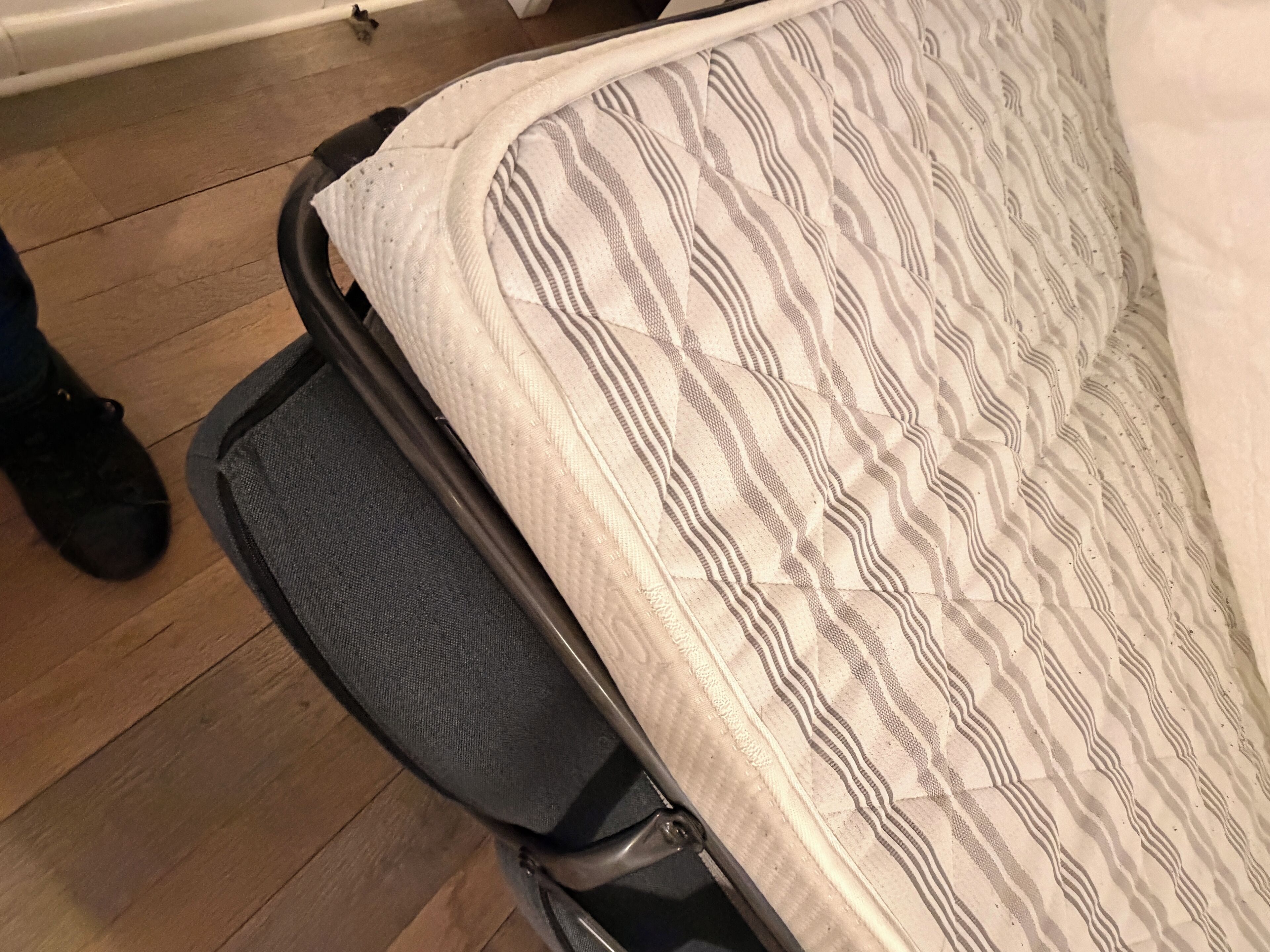 Ein Bett mit einem gemusterten Überwurf und ein grauer Sessel mit strukturierter Sitzfläche.