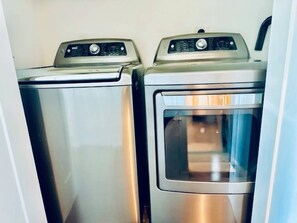 Two stainless steel appliances, likely a washer and dryer, in a compact, modern laundry room. - Dockside Dream Home for 10 (Galveston)