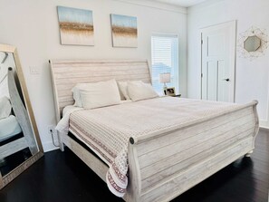 A bedroom with a wooden bed, white bedding, and two landscape paintings on the wall. - Dockside Dream Home for 10 (Galveston)