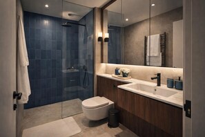 A modern bathroom with a glass-enclosed shower, a white toilet, and a vanity with a sink and mirror. - Beautiful Central Escape | Covent Garden Living (London)