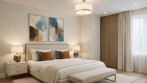 Ein Schlafzimmer mit einem großen Bett, Nachttischen, einer Bank, abstrakter Kunst und einem Kleiderschrank.