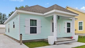 A two-story house with a light blue exterior, a front porch, and a 'WELCOME' sign.