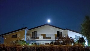 A two-story house with a balcony, a visible moon in the sky, and a well-lit exterior. - Tenuta Albachiara (Naso)