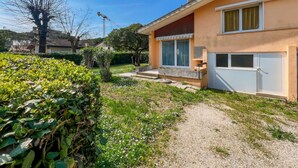 A residential building with a garden, a gravel path, and a clear blue sky. - Bibione Villa With Garden (San Michele al Tagliamento)