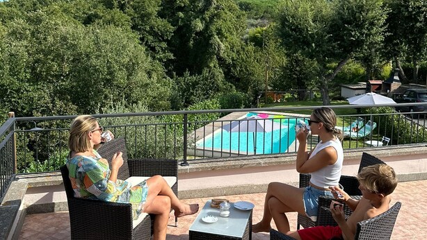A patio with wicker furniture, a pool, and a view of the surrounding greenery. - Cozy independent dwelling immersed in the greenery and quiet of Tuscia (Lazio)
