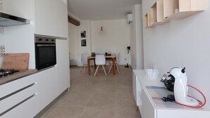 A modern kitchen with white cabinets, a built-in oven, and a dining area with a wooden table and chairs. - Cozy independent dwelling immersed in the greenery and quiet of Tuscia (Lazio)