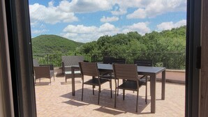 An outdoor patio with tables and chairs, a view of green hills, and a clear sky. - Cozy independent dwelling immersed in the greenery and quiet of Tuscia (Lazio)