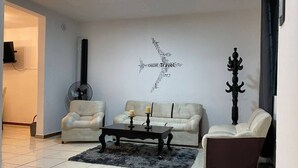 A living room with two sofas, a coffee table, a wall-mounted fan, and a decorative pillar.