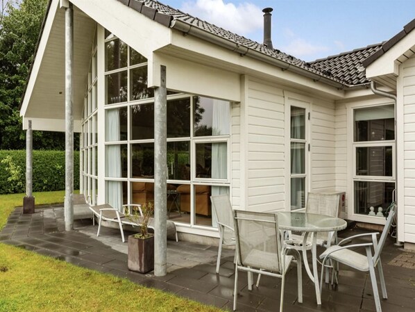 A covered patio area with a table and chairs, large windows, and a chimney. - "Elizabeth" - 175m from the sea by Interhome (Aabenraa)