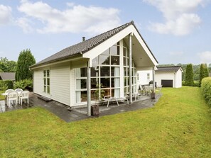 A two-story house with a large glass window wall, a covered patio with outdoor furniture, and a well-maintained lawn. - "Elizabeth" - 175m from the sea by Interhome (Aabenraa)