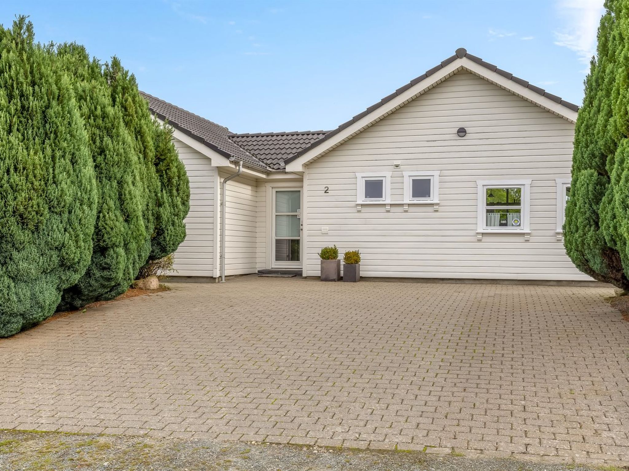 Een herenhuis met een geplaveid oprit en een kleine voortuin.