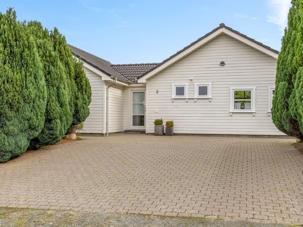 Une maison à deux étages avec une allée pavée et un petit jardin devant.