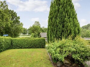 A well-maintained garden with a tall coniferous tree, neatly trimmed hedges, and a stone wall. - "Elizabeth" - 175m from the sea by Interhome (Aabenraa)