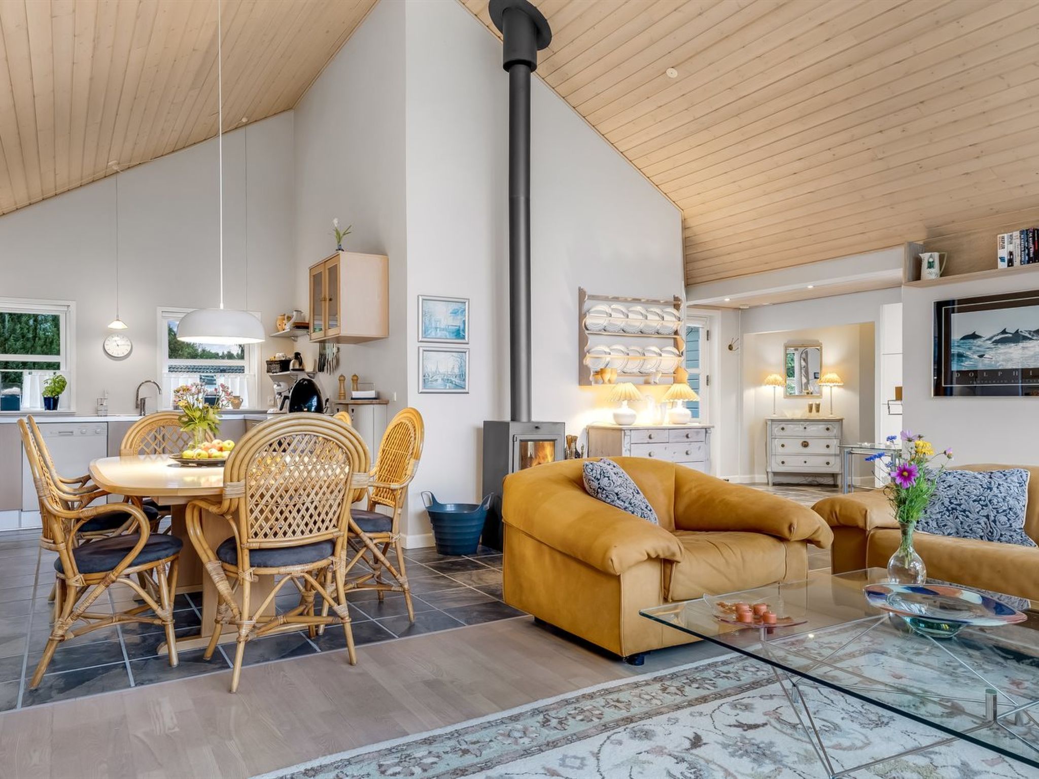 Un vaste espace de vie doté d’un haut plafond, comprenant une table à manger avec des chaises, un canapé et une table basse.