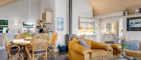 A spacious living area with a high ceiling, a dining table with chairs, a sofa, and a coffee table.
