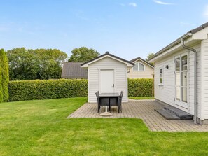Il s'agit d'une propriété résidentielle dotée d'une terrasse dallée, d'un petit abri de jardin et d'une haie.