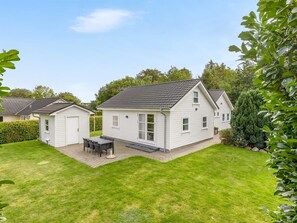 Une maison à deux étages avec un patio couvert et une pelouse.