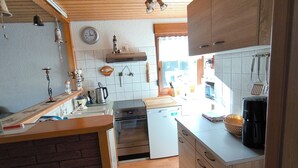 Una cocina compacta con armarios de madera, horno empotrado y cafetera.