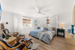A bedroom with a bed, a desk, a chair, a ceiling fan, and a window with curtains. - 1258 Seminole Drive (Indian Harbour Beach)