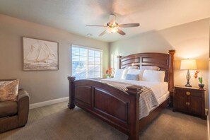 A bedroom with a wooden bed, a ceiling fan, a window with blinds, a nightstand with a lamp, and a chair. - 3BR/2.5BA Townhouse w/ Pool & Hot Tub (Washington)