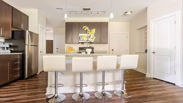 Uma cozinha moderna com ilha central, eletrodomésticos de aço inoxidável e banquetas.