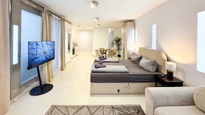 Una habitación de hotel moderna con una cama grande, televisión, escritorio y zona de comedor.