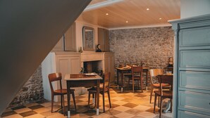 Un comedor con suelo a cuadros, sillas de madera, una mesa y una pared de piedra.