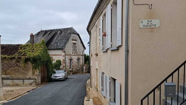 Eine enge Straße mit einem Gebäude auf der rechten Seite, an dem ein Schild mit der Aufschrift "RUE DE LA HUCHETTE" angebracht ist.