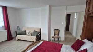 Ein Schlafzimmer mit einem Bett, einem Sofa, einem Sessel und einer Heizung.