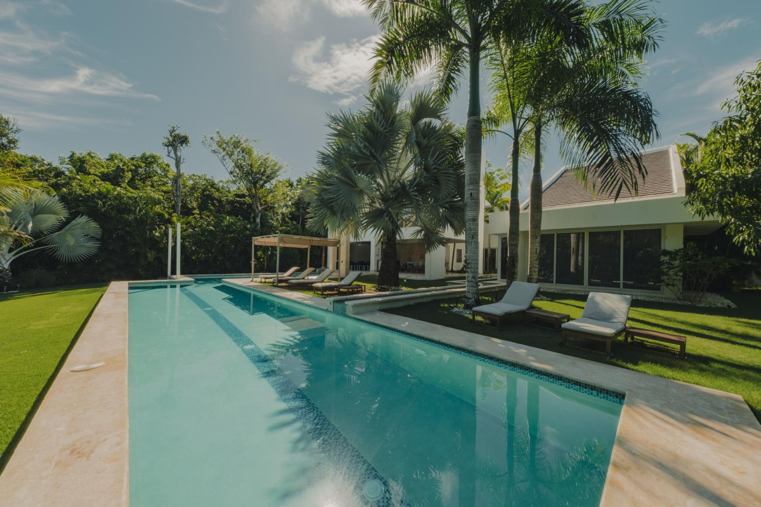 Une piscine avec des chaises longues et des palmiers.