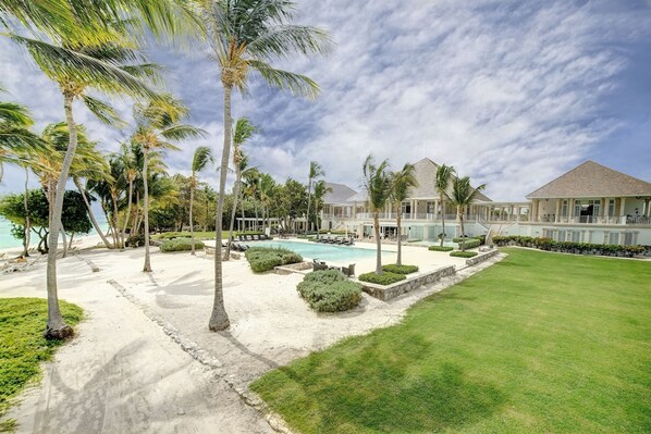 A resort with a pool, palm trees, and a well-maintained lawn. - Corales 50 in Higuey (Punta Cana)