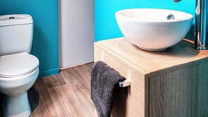 Een badkamer met toilet, wastafel met wasbak en een handdoekhouder.