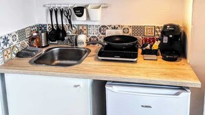 Een kleine keuken met een spoelbak, fornuis en koffiezetapparaat.
