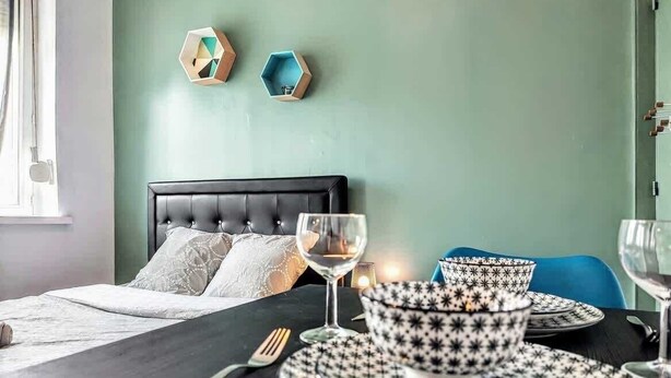 Een net gedekte eettafel met een zwart-wit geruit tafelkleed, een zwart beklede stoel en een blauwe stoel.