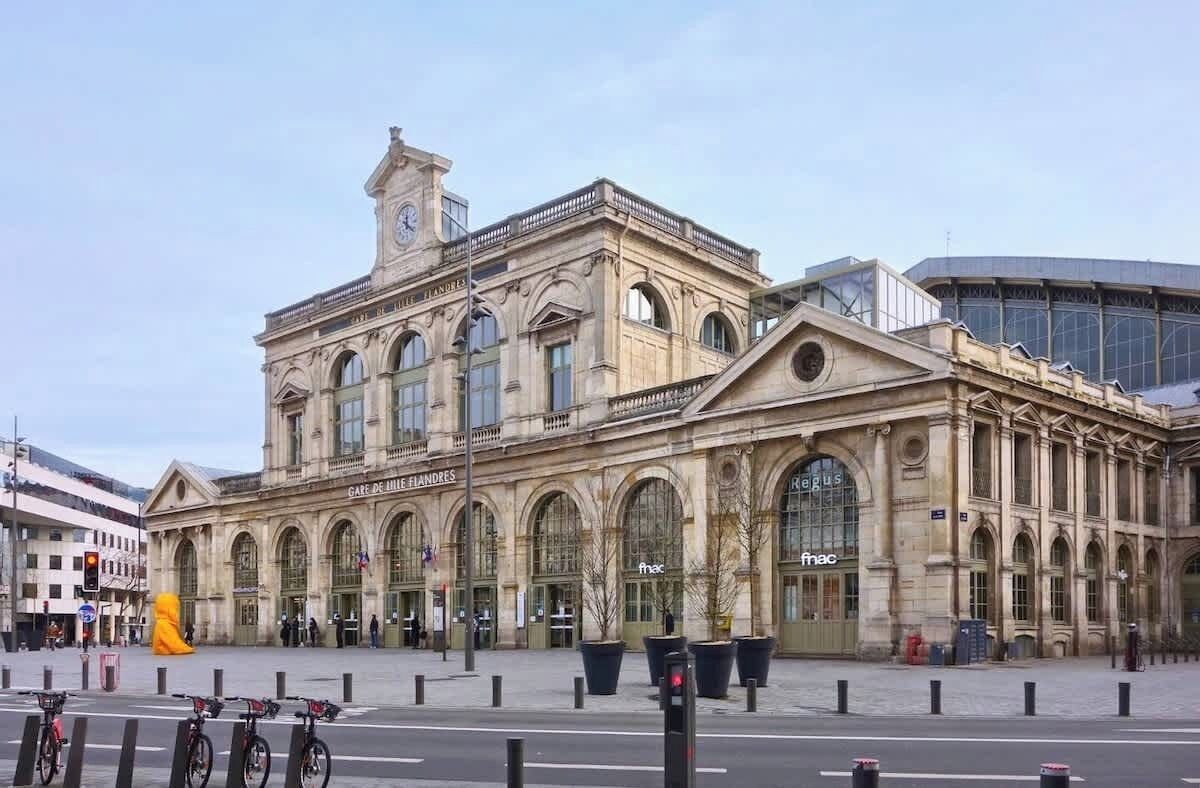 Ein historisches Gebäude mit Rundbogenfenstern und einem Uhrturm, vermutlich ein Bahnhof oder ein öffentliches Gebäude.