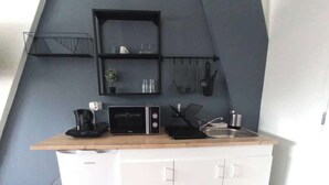 Ett litet, praktiskt kök med mikrovågsugn, kaffebryggare och ett litet handfat.