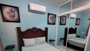 Ein Schlafzimmer mit einem Bett, einem Kleiderschrank, einem Spiegel und einer Klimaanlage.