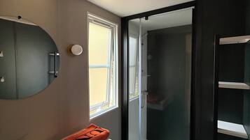 Een moderne badkamer met een grote spiegel, een witte wastafel en een douchecabine met een glazen deur.
