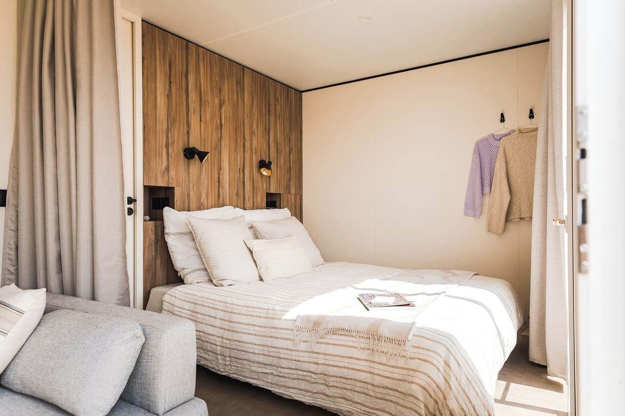 Una camera da letto moderna con un letto, un divano e una parete d'accento in legno.