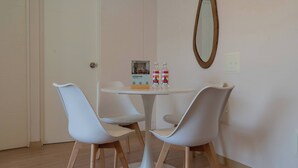 A small, modern room with a round table and two white chairs, a mirror on the wall, and a door. - w* | Amazing 1BR w/ Balcony in Barranco (Barranco)