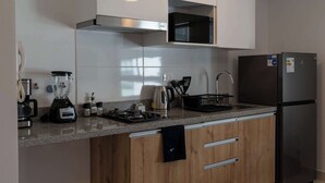 A modern kitchen with a stainless steel refrigerator, a built-in microwave, a coffee maker, a kettle, and a blender. - w* | Amazing 1BR w/ Balcony in Barranco (Barranco)