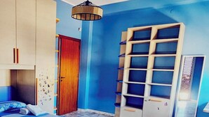 Ein Zimmer mit einem Bett, einem Kleiderschrank und einem großen Bücherregal.